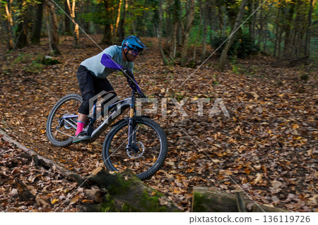 Dynamic Mountain Biker Navigates a Leafy Fall Forest Trail on Rugged Terrain Dynamic Mountain Biker Navigates a Leafy Fall Forest Trail on Rugged Terrain 136119726