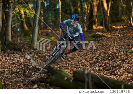 Mountain Biker Navigates Forest Trail in Autumn Colors and Gear 136119738