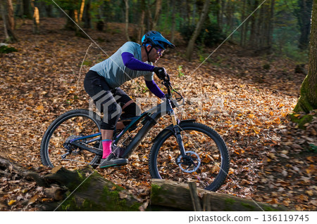 Mountain Biker Navigates Leaf-Covered Forest Trail in Autumn Adventure Mountain Biker Navigates Leaf-Covered Forest Trail in Autumn Adventure 136119745