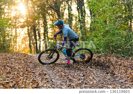 Mountain Biker Navigates Forest Trail Through Autumn Leaves On A Sunny Day Ride Mountain Biker Navigates Forest Trail Through Autumn Leaves On A Sunny Day Ride 136119803