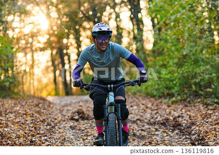 Mountain Biker Enjoys a Sunny Autumn Forest Trail Ride in Helmet, Gear, and Focus 136119816