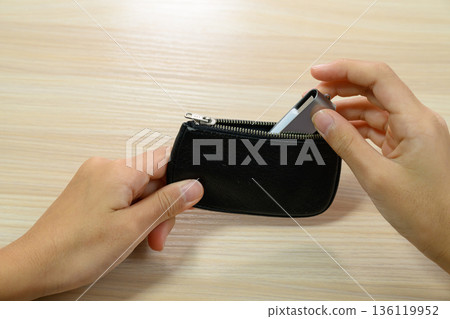 雙手拿著一個裝在黑色小袋子裡的U盤 136119952