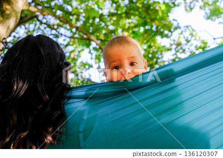 Mother and baby in teal hammock outdoors Mother and baby in teal hammock outdoors 136120307