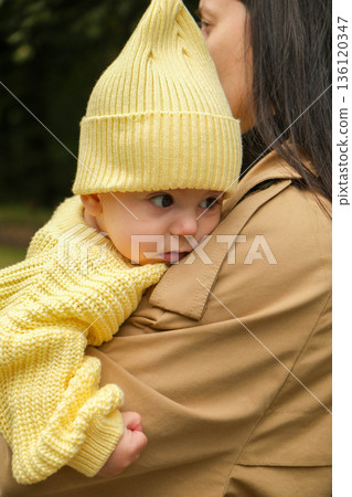 Mother Holding Baby in Yellow Outfit at Park Mother Holding Baby in Yellow Outfit at Park 136120347