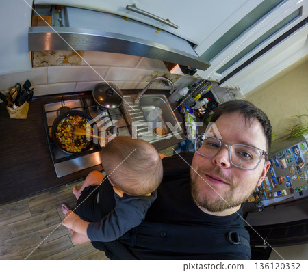 Father Cooking with Baby in Carrier 136120352