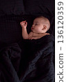Peaceful baby sleeping on dark bedding 136120359