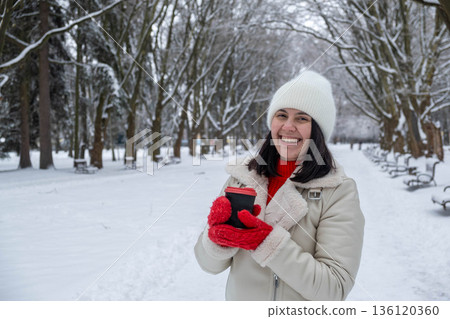 Woman Enjoying Hot Drink in Snowy Park Woman Enjoying Hot Drink in Snowy Park 136120360
