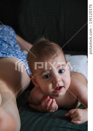 Playful Baby Lying on Bed 136120376