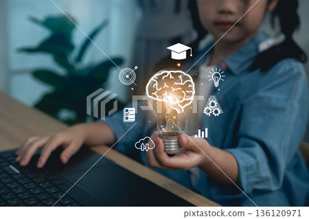 Close-up, Hand girl holding light bulb with brain icon and educational graphics, concept of creative thinking, inspiration, knowledge, smart learning, and intellectual development for kids Close-up, Hand girl holding light bulb with brain icon and educational graphics, concept of creative thinking, inspiration, knowledge, smart learning, and intellectual development for kids 136120971