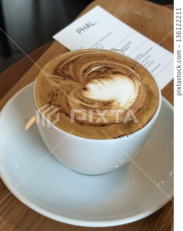A beautifully crafted latte, featuring creamy foam art on top of rich espresso. Perfect for coffee-related projects, this image captures the warmth and inviting nature of a classic café experience. A beautifully crafted latte, featuring creamy foam art on top of rich espresso. Perfect for coffee-related projects, this image captures the warmth and inviting nature of a classic café experience. 136122211