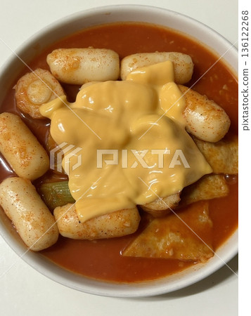Spicy Korean tteokbokki with chewy rice cakes in a vibrant red sauce, topped with sesame seeds and green onions. A popular street food known for its addictive flavor and satisfying texture. 136122268