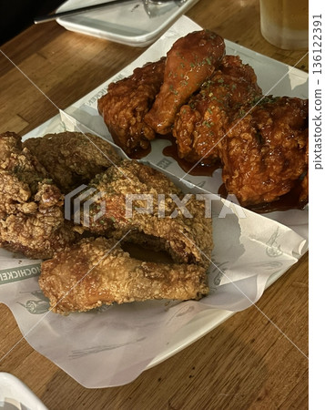 Crispy Korean fried chicken, perfectly glazed with a sweet and spicy sauce. Ideal for food photography and menus, showcasing the irresistible crunch and flavor of this beloved dish. 136122391