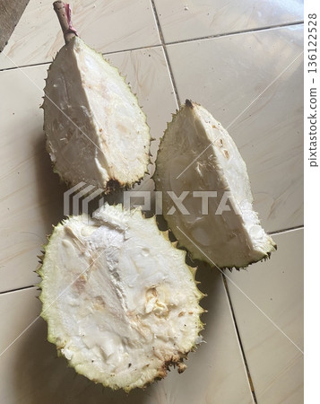 Poor quality durian with uneven shape, dull color, and cracked or damaged skin, showing signs of overripeness or spoilage with an unappealing and less fresh appearance compared to good quality fruit Poor quality durian with uneven shape, dull color, and cracked or damaged skin, showing signs of overripeness or spoilage with an unappealing and less fresh appearance compared to good quality fruit 136122528