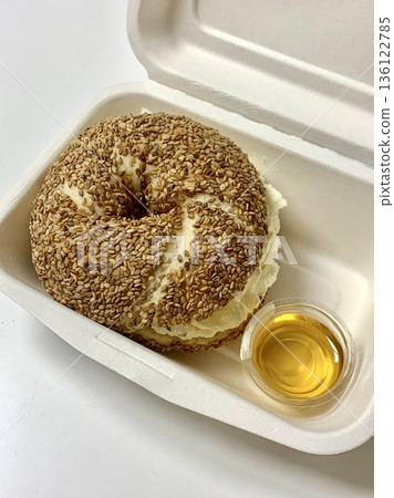 A fresh bagel sandwich filled with layers of smoked salmon, cream cheese, lettuce, and tomato. The golden-brown bagel adds a delightful texture to this classic combination. 136122785