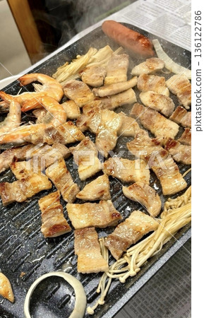 Grilled samgyeopsal, showcasing thick slices of pork belly sizzling on the grill. A popular Korean barbecue dish, capturing the essence of a delicious dining experience. Grilled samgyeopsal, showcasing thick slices of pork belly sizzling on the grill. A popular Korean barbecue dish, capturing the essence of a delicious dining experience. 136122786