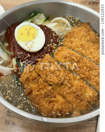 Naengmyeon, a refreshing Korean cold noodle dish served in an icy broth, topped with sliced vegetables, a boiled egg, and spicy sauce. Perfect for summer food photography and Korean cuisine projects. Naengmyeon, a refreshing Korean cold noodle dish served in an icy broth, topped with sliced vegetables, a boiled egg, and spicy sauce. Perfect for summer food photography and Korean cuisine projects. 136122833