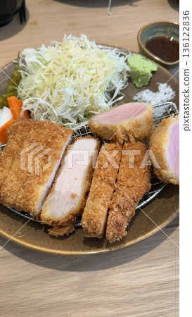 Crispy tonkatsu, a Japanese-style breaded and deep-fried pork cutlet, served with shredded cabbage and drizzled with savory sauce. A delightful balance of crunchy texture and juicy meat. 136122836