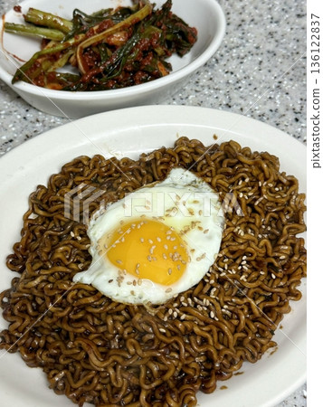Savory jjapagetti noodles with a rich black bean sauce, topped with green onions and sesame seeds. A comforting Korean favorite that combines depth and flavor in each bite. 136122837