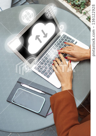 Person using a laptop with cloud symbols on the screen at an outdoor workspace 136122928