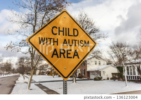 Yellow child with autism area road warning sign in residential neighborhood with winter houses and trees in the United States 136123004