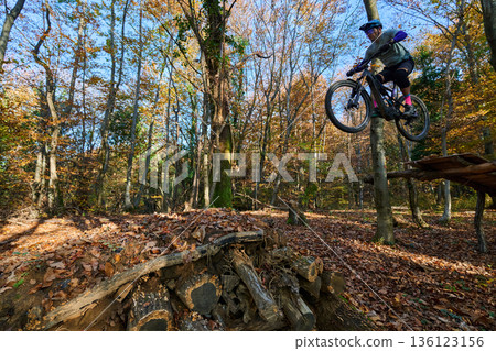 Autumn Mountain Biker Performs High Jump Through Leafy Forest Trail Scene Autumn Mountain Biker Performs High Jump Through Leafy Forest Trail Scene 136123156