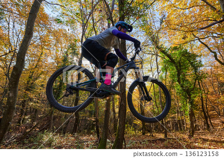 Thrilling Autumn Mountain Biking Jump Through a Colorful Forest Trail 136123158