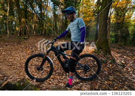 Mountain Biker in Forest Trail Wearing Helmet and Knee Pads During Autumn Ride Mountain Biker in Forest Trail Wearing Helmet and Knee Pads During Autumn Ride 136123201