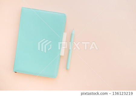 Angled turquoise notebook with pen and sticky note on pastel desk background 136123219