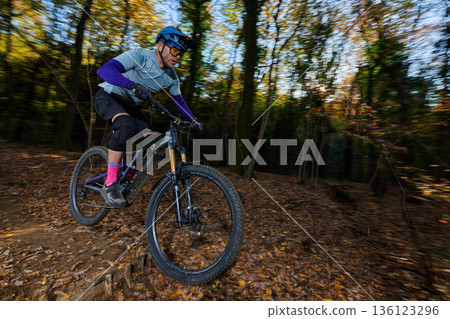 Autumn Forest Mountain Bike Rider Navigates Leaf-Covered Trail With Speed and Focus In Sunlit Forest Autumn Forest Mountain Bike Rider Navigates Leaf-Covered Trail With Speed and Focus In Sunlit Forest 136123296
