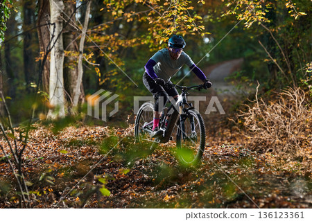 Autumn Mountain Biker Navigates Leafy Forest Trail On Rough Terrain Autumn Mountain Biker Navigates Leafy Forest Trail On Rough Terrain 136123361