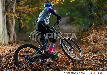 Mountainbike Rider Navigating Autumn Forest Trail in Gear with Colorful Socks Mountainbike Rider Navigating Autumn Forest Trail in Gear with Colorful Socks 136123365