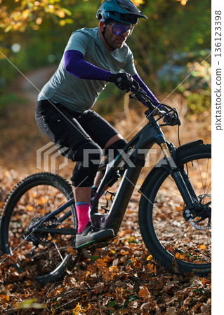 Mountain Biker On Leafy Autumn Trail In Helmet, Gear, And Bright Socks Mountain Biker On Leafy Autumn Trail In Helmet, Gear, And Bright Socks 136123398