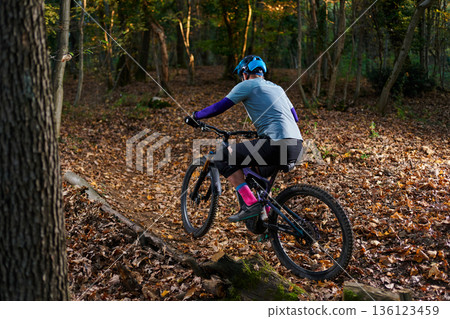 Mountain Biker Navigates Leaf-Covered Trail Through Autumn Forest Mountain Biker Navigates Leaf-Covered Trail Through Autumn Forest 136123459
