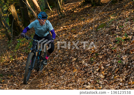 Male Mountain Biker Riding Through Forest Trail on Leaf-Littered Path in Autumn Male Mountain Biker Riding Through Forest Trail on Leaf-Littered Path in Autumn 136123538