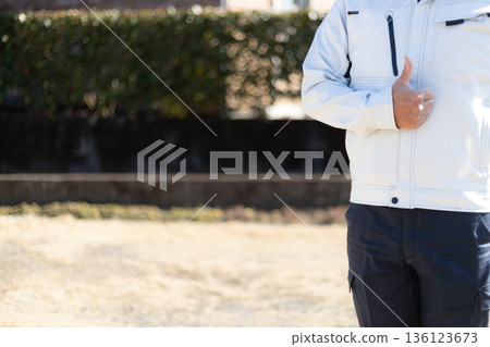 A man in work clothes gives a thumbs up and shows approval. A man gives a thumbs up and shows approval. 136123673