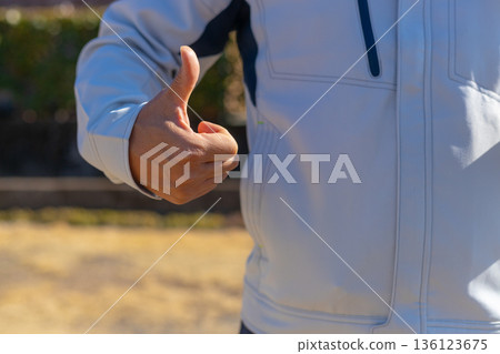 A man in work clothes gives a thumbs up and shows approval. A man gives a thumbs up and shows approval. 136123675