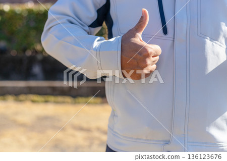 A man in work clothes gives a thumbs up and shows approval. A man gives a thumbs up and shows approval. 136123676