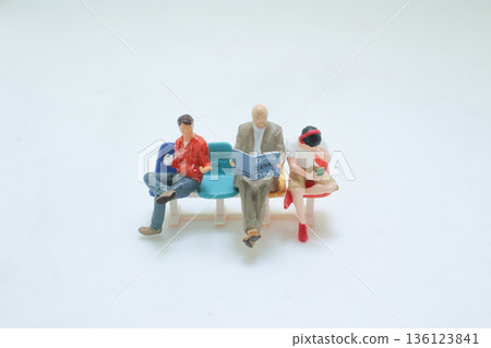 Miniature Figures Sitting Comfortably On Colorful Plastic Seats Miniature Figures Sitting Comfortably On Colorful Plastic Seats 136123841