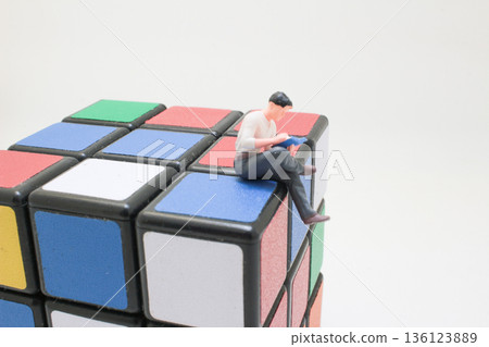 Miniature Reader Sitting Quietly Atop Colorful Rubik Cube Miniature Reader Sitting Quietly Atop Colorful Rubik Cube 136123889