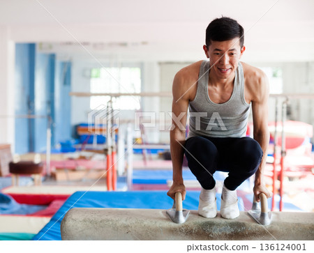 Male gymnast performing exercise on pommel horse Male gymnast performing exercise on pommel horse 136124001