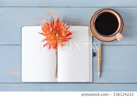 Top view of the desktop. Spiral notebook with an open blank page, pen, white cup with black coffee, dahlia flowers. Festive office desktop concept. Morning coffee cup. Top view of the desktop. Spiral notebook with an open blank page, pen, white cup with black coffee, dahlia flowers. Festive office desktop concept. Morning coffee cup. 136124222