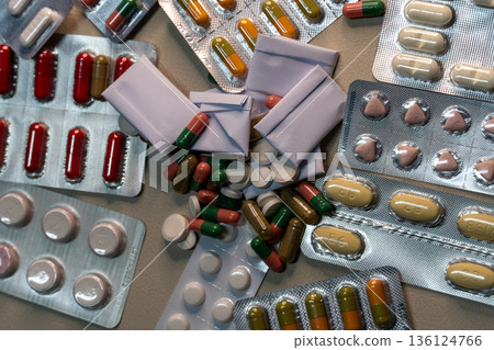 Various pills and capsules scattered with medicine blisters and packages 136124766