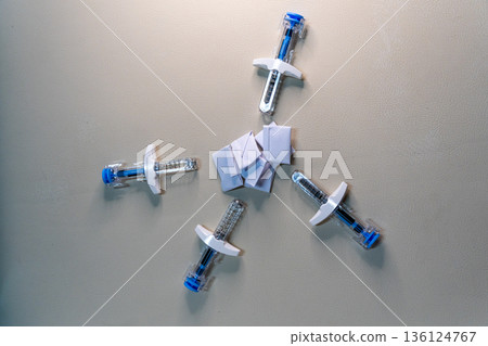 Medical syringes protecting a stack of wrinkled papers 136124767