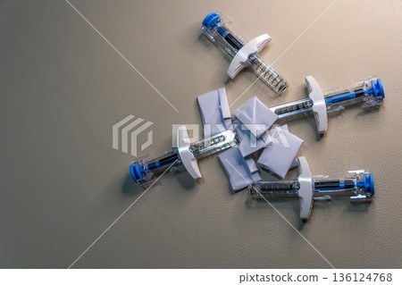 Administering medication with pre filled syringes and alcohol swabs on beige surface 136124768