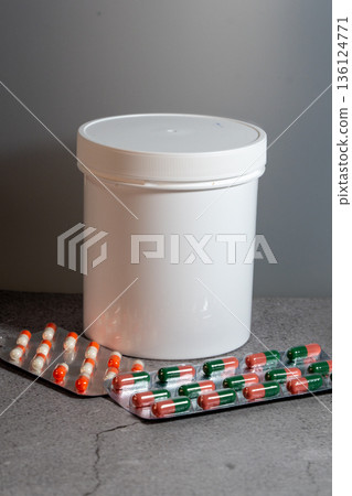 White jar and blister packs with medicine capsules 136124771