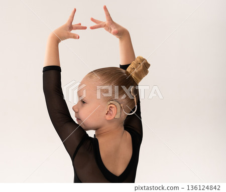 Young dancer with cochlear implant performing expressive sport dance movement. Hearing loss rehabilitation, auditory therapy, assistive technology, physical coordination, and confidence growth 136124842