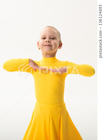 Young girl with cochlear implant performing sport dance in yellow costume on studio background. Hearing loss treatment, auditory rehabilitation, assistive technology, inclusive childhood, and 136124893