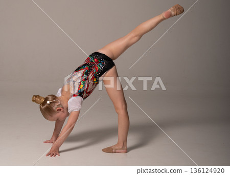Child gymnast with cochlear implant performing balance pose on floor. Hearing loss rehabilitation, cochlear implant therapy, inclusive physical training, postural control, and pediatric recovery Child gymnast with cochlear implant performing balance pose on floor. Hearing loss rehabilitation, cochlear implant therapy, inclusive physical training, postural control, and pediatric recovery 136124920