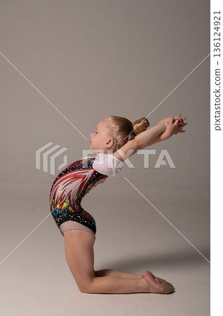 Rhythmic gymnastics child with cochlear implant performing backbend exercise. Hearing loss treatment, cochlear implantation recovery, body awareness, inclusive training, and pediatric rehabilitation 136124921