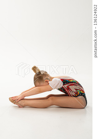 Rhythmic gymnast child with cochlear implant performing forward stretch pose. Hearing rehabilitation therapy, cochlear implantation recovery, inclusive sport, sensory integration, and childhood motor Rhythmic gymnast child with cochlear implant performing forward stretch pose. Hearing rehabilitation therapy, cochlear implantation recovery, inclusive sport, sensory integration, and childhood motor 136124922